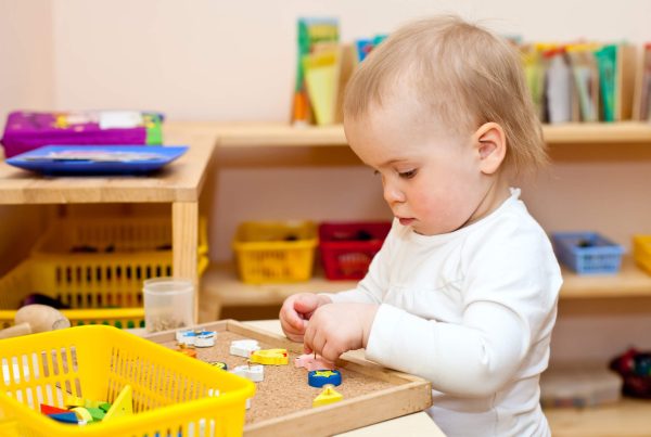 Child at nursery. Little baby girl playing with wooden toys at nursery