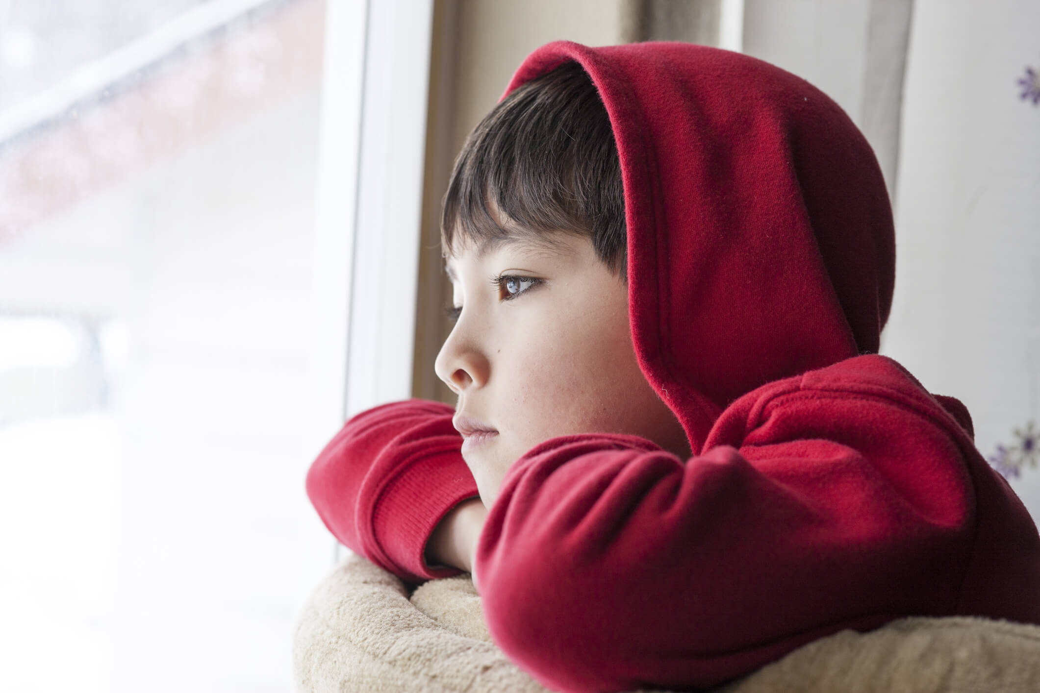 Boy looks outside. A young boy appears to be bored and stuck indoors.