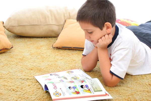 Boy reading a book on the floor. Boy in a room reading a book over a carpet. He looks interested and concentrated. Visit my gallery for more images of children