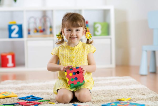Child preschooler girl plays logical toy learning shapes and colors